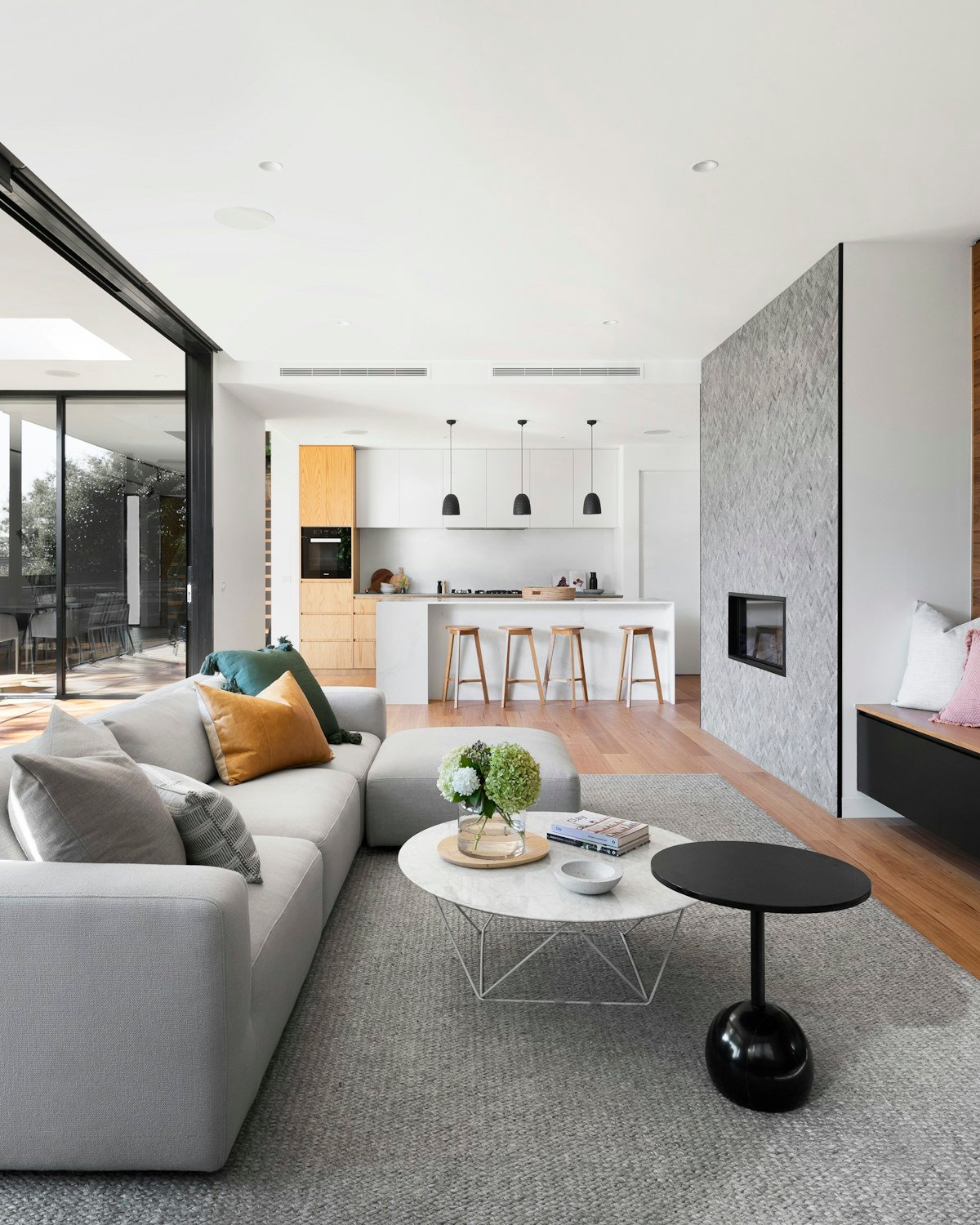 Open-plan Ottawa living room with renovated kitchen and herringbone tile fireplace surround