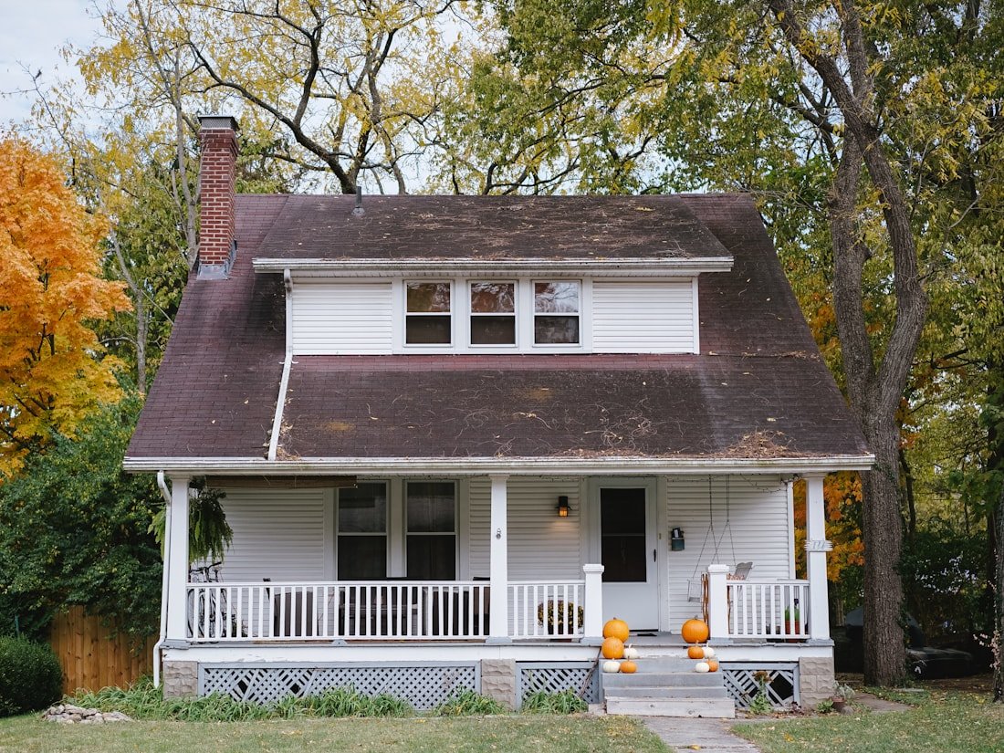 Heritage Ottawa home with white siding wraparound porch in autumn